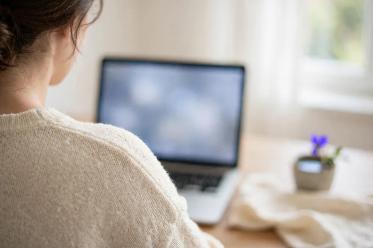 A person exporting a file at a laptop, seen from behind